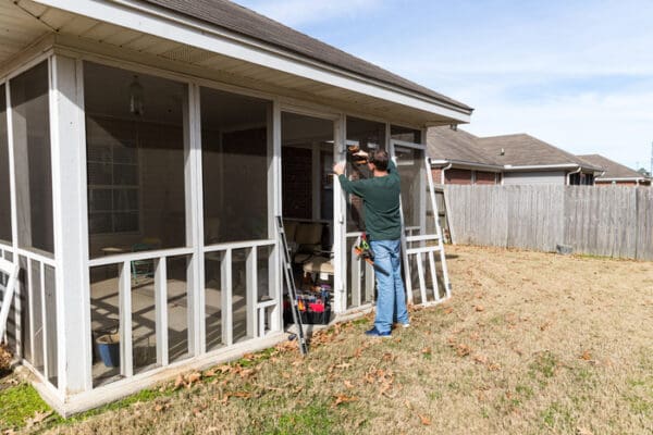 expert works on repairing Patio Screen Repair in back porch